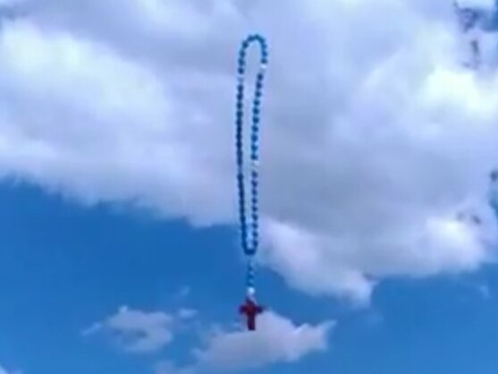 Foto: ein Holzkreuz steigt mit Luftballons in Ghana in den Himmel