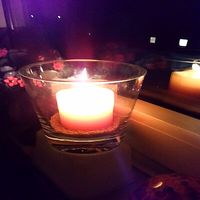 Foto: eine brennende Kerze eines Gemeindegliedes im Fenster